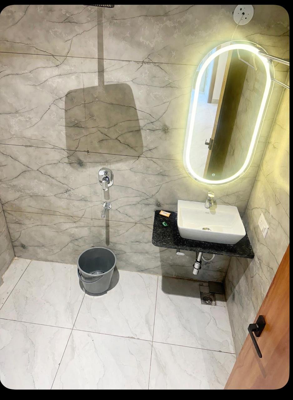 Bathroom with marble cladding, a granite counter and a backlit mirror