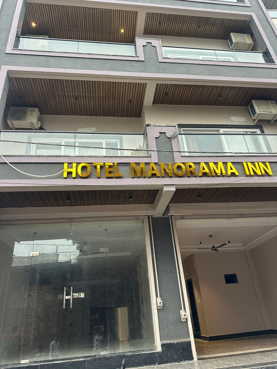 Street frontage of Hotel Manorama Inn with gold lettering above the ground-floor glazing